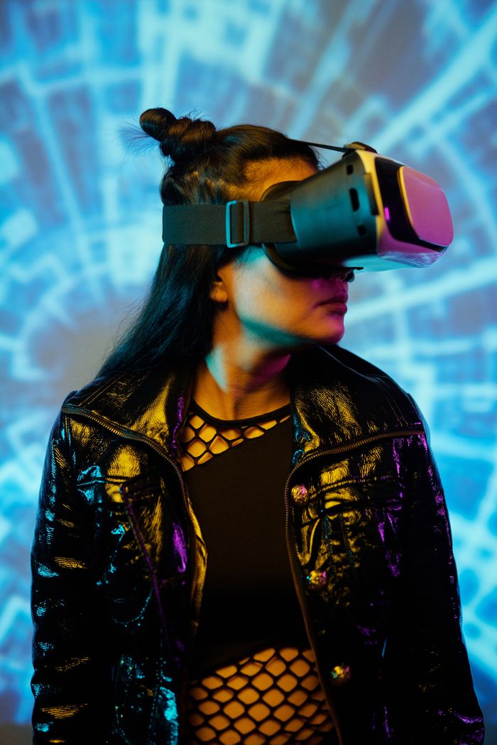 gallery-2 Stylish Asian woman immersed in virtual reality with futuristic glowing backdrop.