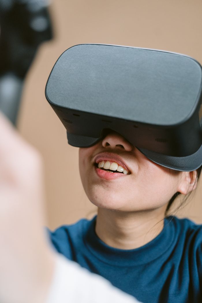 A woman wearing a VR headset smiles and engages with virtual content indoors.