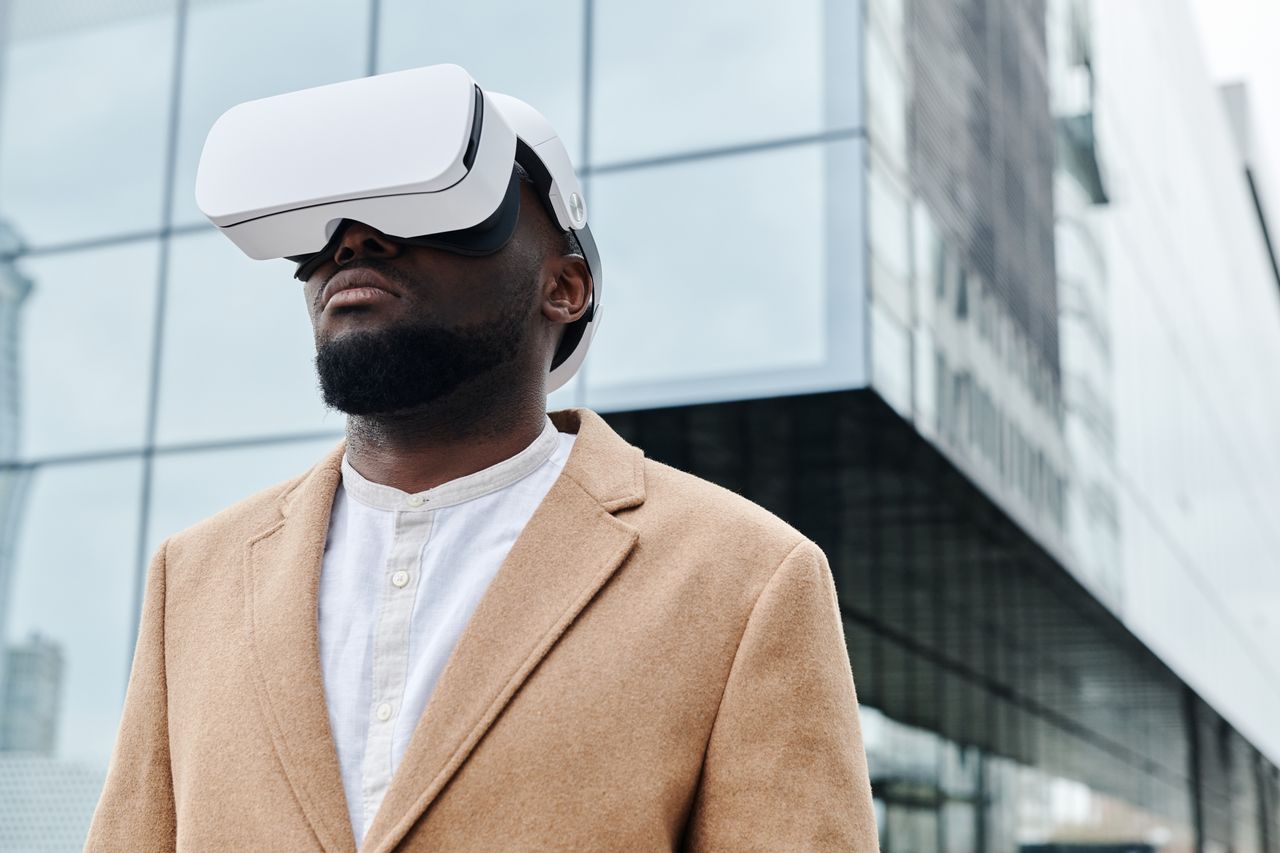 about-01 A man wearing VR glasses and a coat, engaging with virtual reality technology outdoors.